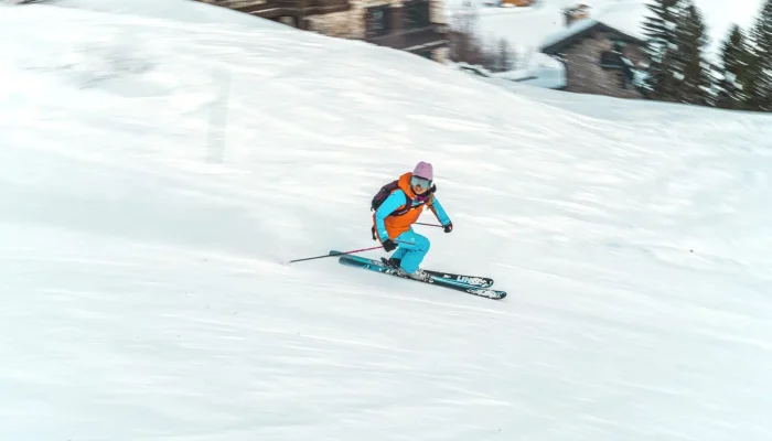 An Oxygène Ski School instructor skiing in the Ubaye Valley resort, with snowy alpine mountains in the background.