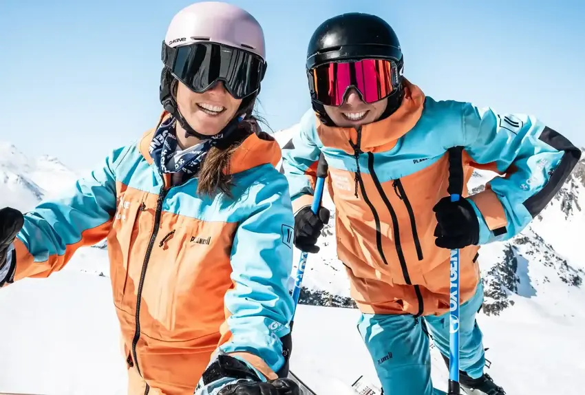 Two smiling Oxygène instructors at the top of a mountain.